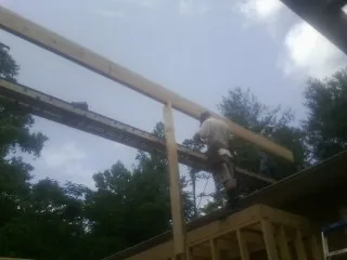 Carpenter setting a ridge beam over a new addition frame — Ice Dam Removal by Roofing Brothers in Dansville