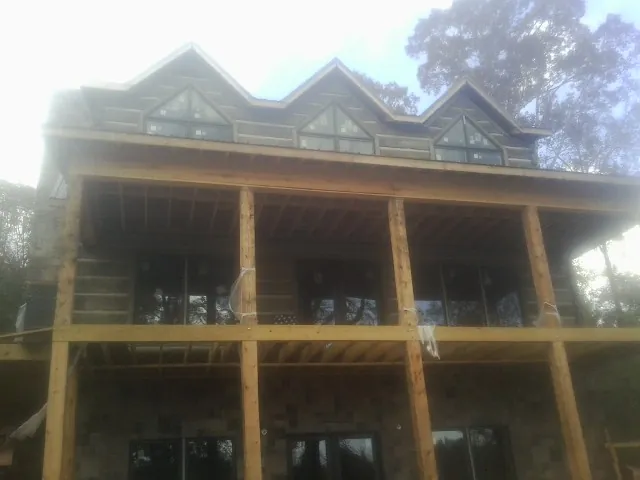 Dormers and porch framing on a large log home under construction — Roof Coating work by our crew in Dansville
