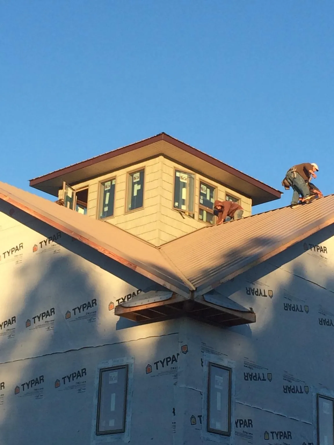 Roofers working around a rooftop cupola on a new metal roof at sunset — Roof Waterproofing in Dansville by Roofing Brothers
